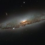 This NASA/ESA Hubble Space Telescope image shows the spiral galaxy NGC 4845, located over 65 million light-years away in the constellation of Virgo (The Virgin). The galaxy’s orientation clearly reveals the galaxy’s striking spiral structure: a flat and dust-mottled disc surrounding a bright galactic bulge. NGC 4845’s glowing centre hosts a gigantic version of a black hole, known as a supermassive black hole. The presence of a black hole in a distant galaxy like NGC 4845 can be inferred from its effect on the galaxy’s innermost stars; these stars experience a strong gravitational pull from the black hole and whizz around the galaxy’s centre much faster than otherwise. From investigating the motion of these central stars, astronomers can estimate the mass of the central black hole — for NGC 4845 this is estimated to be hundreds of thousands times heavier than the Sun. This same technique was also used to discover the supermassive black hole at the centre of our own Milky Way — Sagittarius A* — which hits some four million times the mass of the Sun (potw1340a). The galactic core of NGC 4845 is not just supermassive, but also super-hungry. In 2013 researchers were observing another galaxy when they noticed a violent flare at the centre of NGC 4845. The flare came from the central black hole tearing up and feeding off an object many times more massive than Jupiter. A brown dwarf or a large planet simply strayed too close and was devoured by the hungry core of NGC 4845.